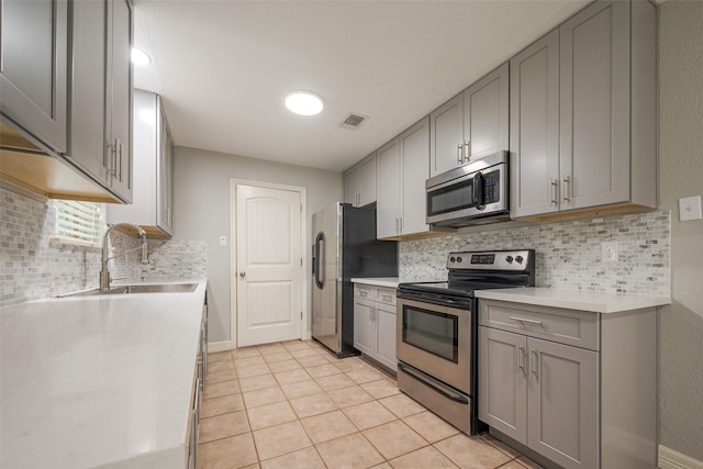 kitchen with stainless steel appliances, light countertops, visible vents, gray cabinetry, and a sink