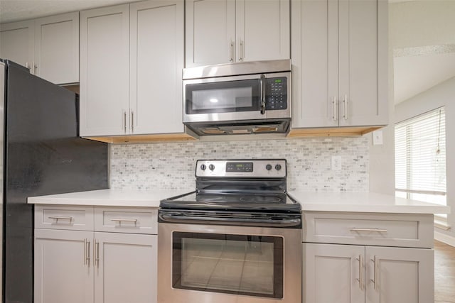 kitchen featuring tasteful backsplash, stainless steel appliances, and light countertops