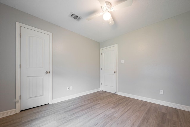 spare room with a ceiling fan, visible vents, baseboards, and wood finished floors