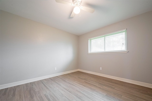 empty room with wood finished floors, a ceiling fan, and baseboards