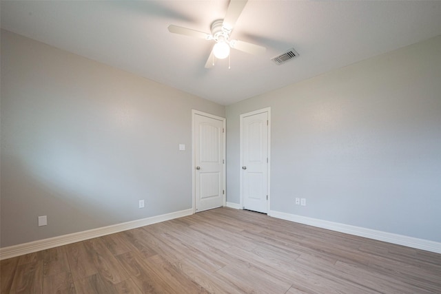 spare room with light wood finished floors, baseboards, visible vents, and ceiling fan