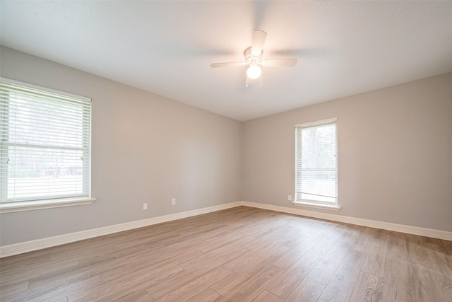 spare room featuring light wood finished floors, a ceiling fan, and baseboards