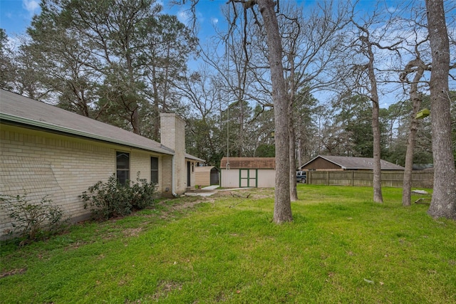 view of yard with a shed, fence, and an outbuilding