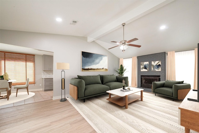 living area with vaulted ceiling with beams, light wood-style flooring, a fireplace, visible vents, and a ceiling fan