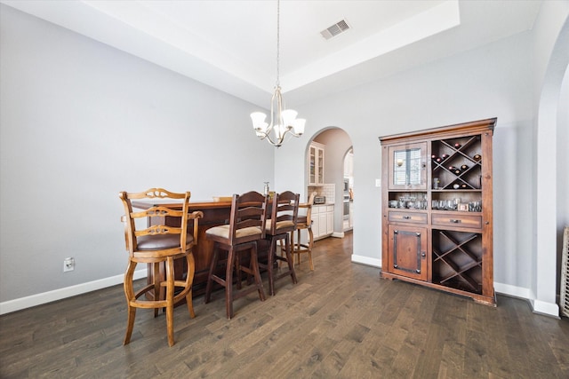 dining room with dark wood-style floors, arched walkways, a tray ceiling, visible vents, and baseboards