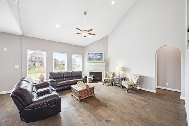 living area featuring arched walkways, a glass covered fireplace, and dark wood finished floors