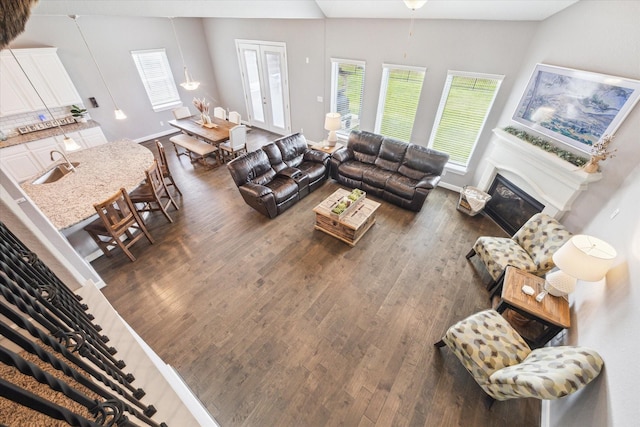 living area with lofted ceiling, baseboards, dark wood finished floors, and a glass covered fireplace