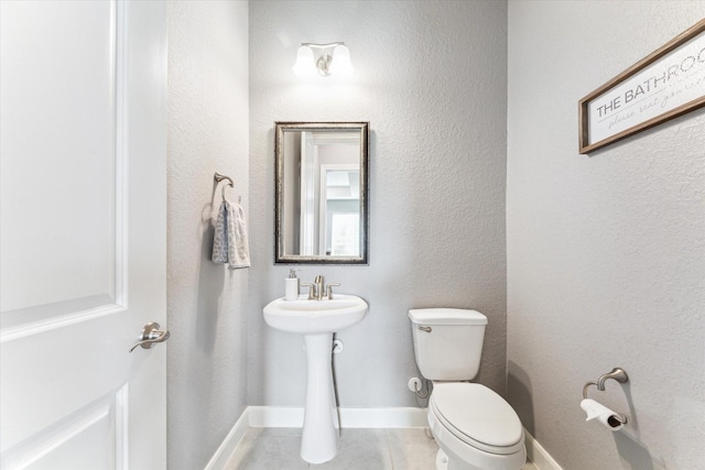 bathroom featuring tile patterned flooring, baseboards, and toilet