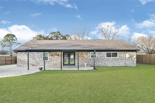 rear view of house with french doors, brick siding, a patio, a lawn, and a fenced backyard