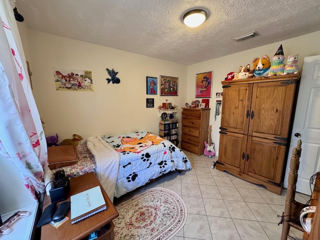 bedroom featuring light tile patterned floors, a textured ceiling, and visible vents