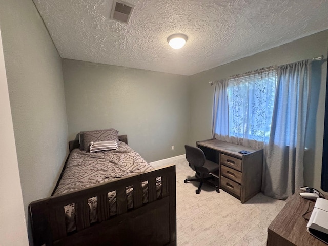 bedroom featuring a textured ceiling, light colored carpet, visible vents, and baseboards