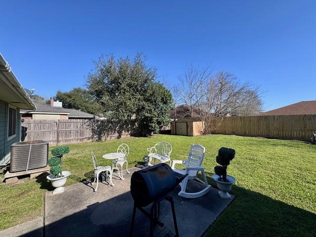 view of yard featuring an outbuilding, central AC unit, a fenced backyard, a shed, and a patio area