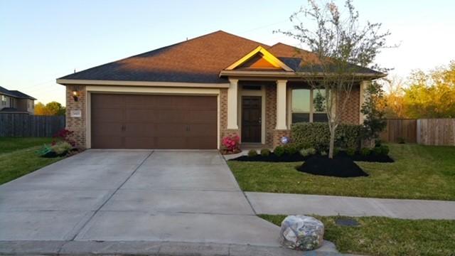 view of front of house with an attached garage, brick siding, fence, driveway, and a front yard