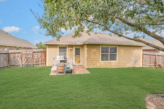 rear view of property featuring a fenced backyard, a lawn, and roof with shingles