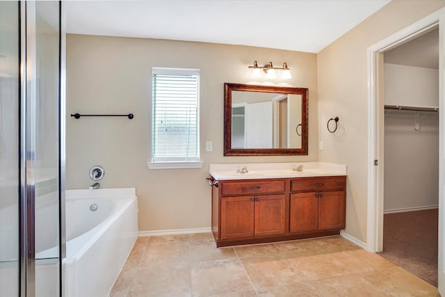 bathroom with a garden tub, a sink, baseboards, a spacious closet, and double vanity