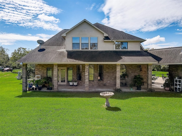 view of front of house featuring french doors, brick siding, a front lawn, and roof with shingles