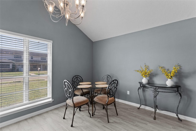 dining space featuring wood finished floors, vaulted ceiling, baseboards, and an inviting chandelier