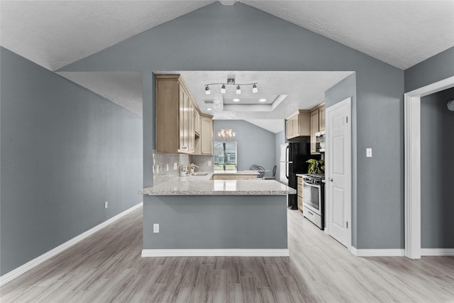 kitchen featuring light wood-style flooring, appliances with stainless steel finishes, a peninsula, a chandelier, and a sink