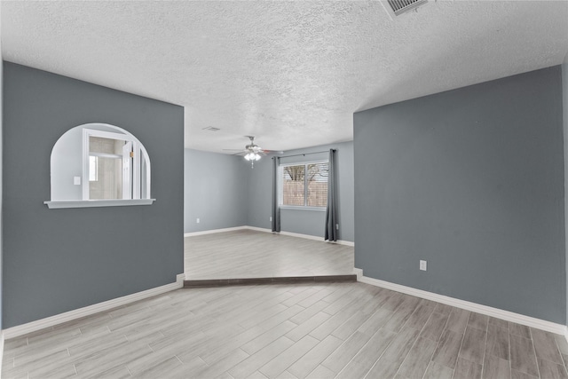 unfurnished living room featuring baseboards, visible vents, ceiling fan, wood finished floors, and a textured ceiling