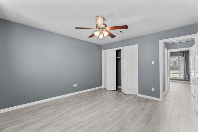 unfurnished bedroom with a closet, visible vents, attic access, wood finished floors, and baseboards