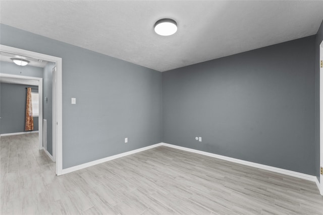 spare room featuring attic access, baseboards, and wood finished floors