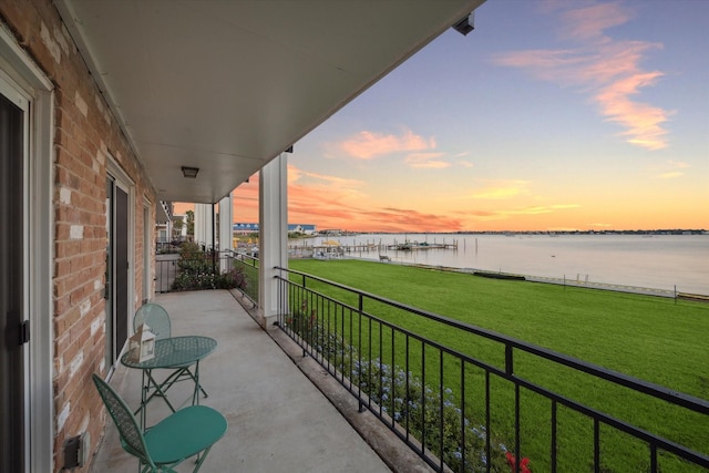 balcony at dusk featuring a water view