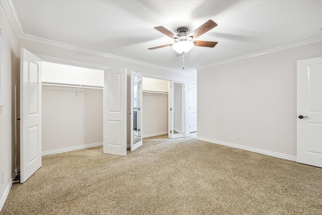 unfurnished bedroom with light carpet, crown molding, and multiple closets