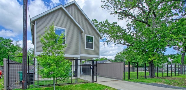 view of front facade featuring concrete driveway, fence, and a gate