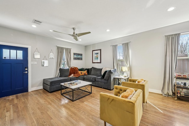 living room with ceiling fan, plenty of natural light, light wood-style flooring, and visible vents