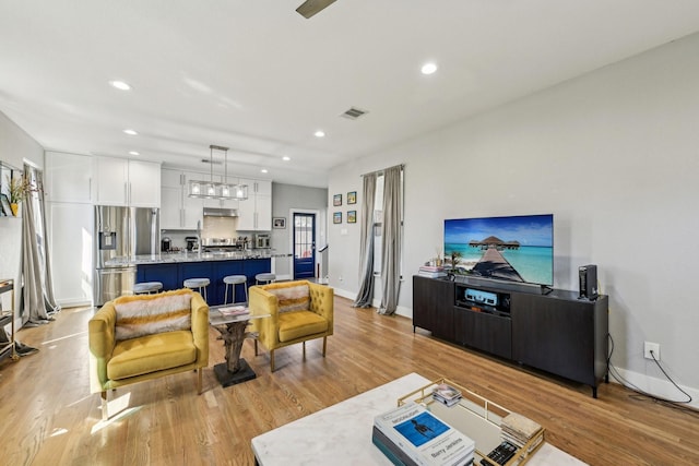 living room with light wood-type flooring, visible vents, and recessed lighting