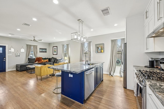 kitchen with appliances with stainless steel finishes, visible vents, a sink, and white cabinetry