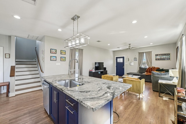 kitchen with stainless steel dishwasher, a sink, light wood-style floors, and blue cabinets