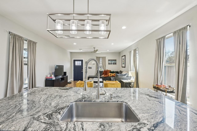 kitchen featuring a sink, stone countertops, recessed lighting, and open floor plan