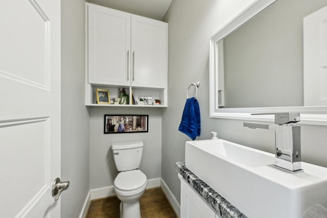 half bath featuring toilet, baseboards, wood finished floors, and vanity