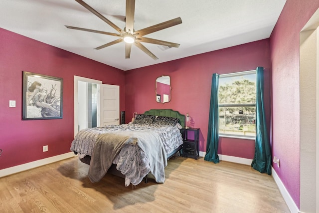 bedroom featuring baseboards, ceiling fan, wood finished floors, and visible vents