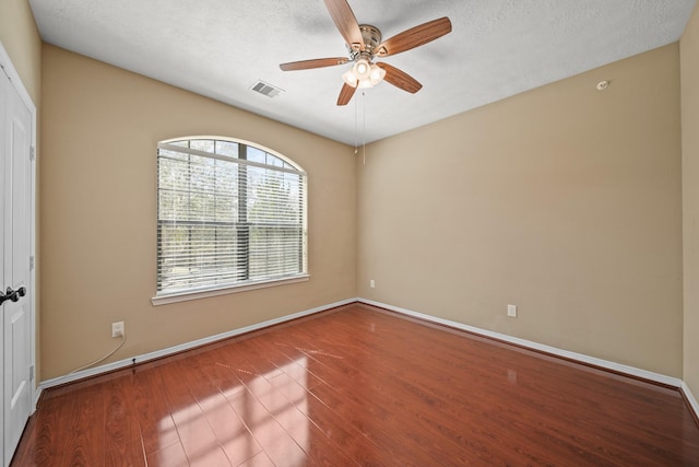 spare room featuring visible vents, a textured ceiling, ceiling fan, and wood finished floors