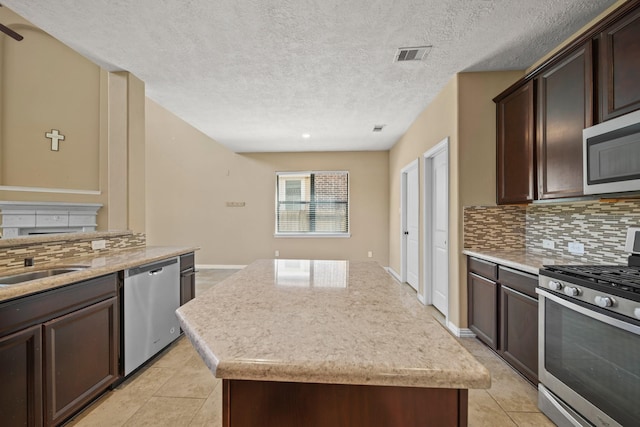 kitchen with visible vents, backsplash, a center island, dark brown cabinetry, and appliances with stainless steel finishes