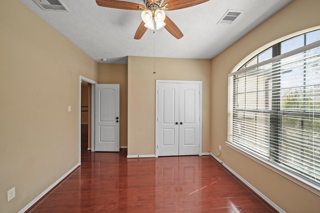 unfurnished bedroom featuring a closet, visible vents, baseboards, and wood finished floors