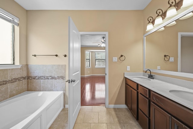 bathroom featuring double vanity, a bath, tile patterned floors, a ceiling fan, and a sink