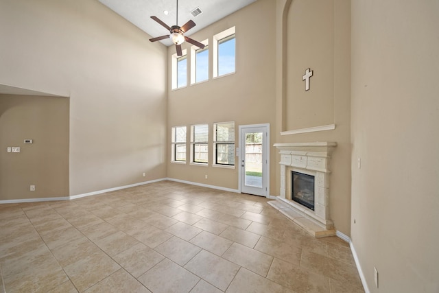 unfurnished living room featuring light tile patterned floors, a glass covered fireplace, baseboards, and ceiling fan