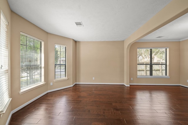 spare room featuring baseboards, wood finished floors, arched walkways, and a textured ceiling