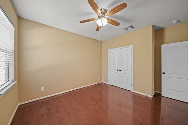 unfurnished bedroom with visible vents, a ceiling fan, baseboards, and wood finished floors