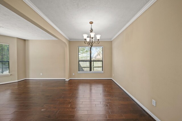 unfurnished room with a notable chandelier, a textured ceiling, crown molding, baseboards, and dark wood-style flooring