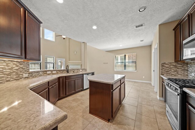 kitchen with visible vents, a kitchen island, dark brown cabinetry, appliances with stainless steel finishes, and a sink