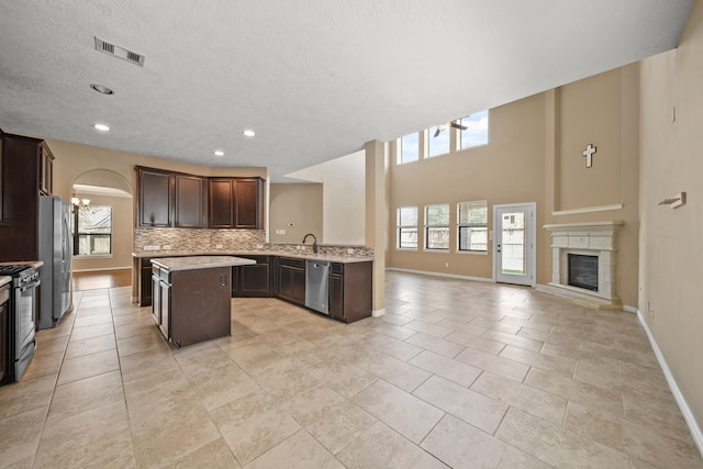 kitchen featuring visible vents, a center island, open floor plan, light countertops, and stainless steel appliances