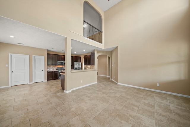 unfurnished living room featuring recessed lighting, baseboards, arched walkways, and light tile patterned floors