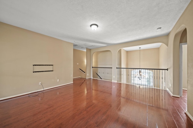 empty room with baseboards, a textured ceiling, and wood finished floors