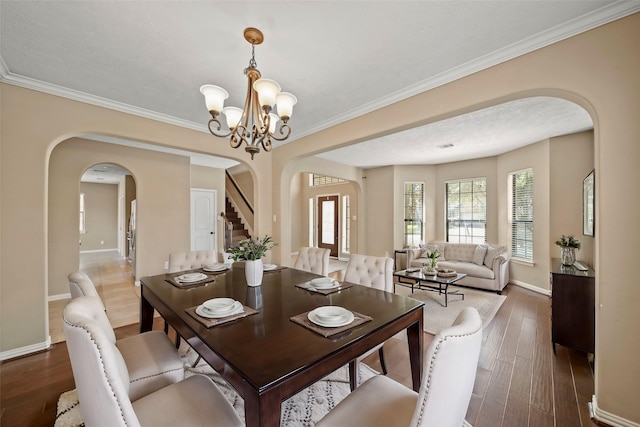 dining space featuring stairway, baseboards, arched walkways, dark wood-style flooring, and a chandelier