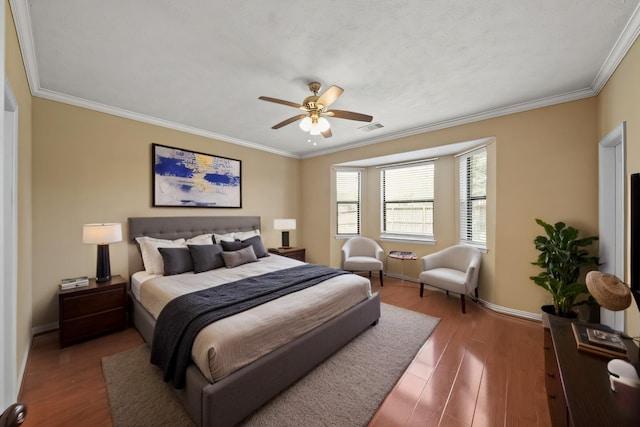 bedroom featuring a ceiling fan, wood finished floors, visible vents, baseboards, and crown molding