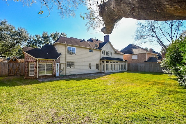 back of house with brick siding, a patio area, a lawn, and a fenced backyard